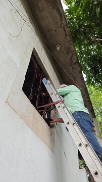 Ladder Secured Against Window Frame While Painter Works