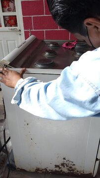 Young Man Applying Painter Masking Tape To Home Stove