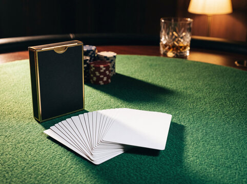 Blank playing card deck mockup fanned out on green felt casino poker table