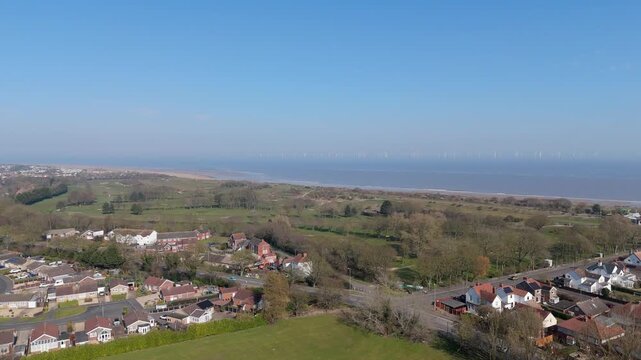 Clear blue skies above green fields and coastal towns