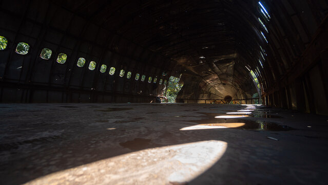 Sunlight streaming through oval windows inside dark abandoned airplane fuselage, urban exploration decay