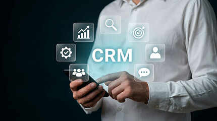 Obraz premium Businessman using mobile phone with CRM software and digital icons graphic