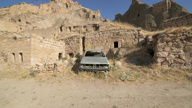 Abandoned car rusts among ruined homes in empty Afghan village scarred by conflict damage.
