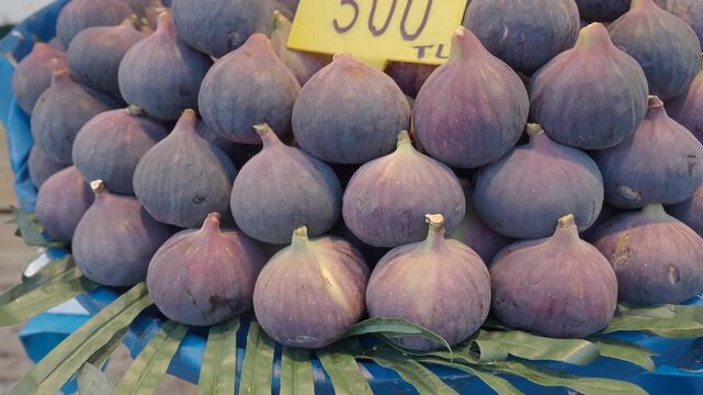 Fresh ripe purple figs stacked at market stall motion footage.
