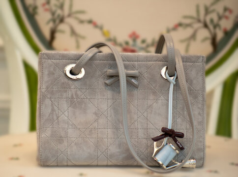 Promenade bag from the Dior Qixi collection in grey suede with a Flat cannage pattern, a decorative bow and a light blue leather charm. Milan, Italy, 26 September 2026