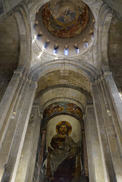 A monumental fresco of Christ Pantocrator occupies the altar apse beneath soaring stone arches and a painted dome inside Svetitskhoveli Cathedral in Mtskheta, Georgia