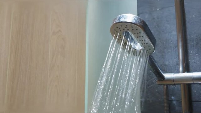 Water flowing from a modern chrome shower head in a contemporary bathroom.