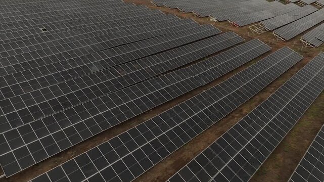 Elevated angle shot showing incomplete mounting racks and installed solar modules on dry ground.