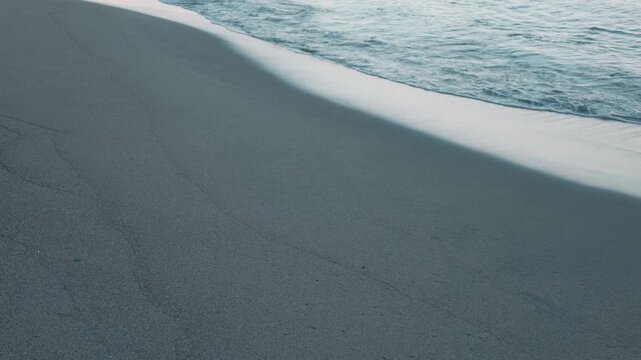 Gentle Waves Breaking on a Wide Blue-Gray Sandy Beach
