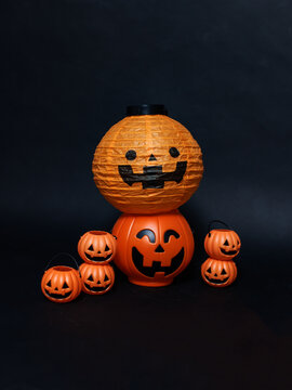 Halloween pumpkin orange lanterns with cheerful jack o lantern faces stacked arranged on black background creating holiday festive thanksgiving spooky atmosphere celebrations seasonal funny decoration