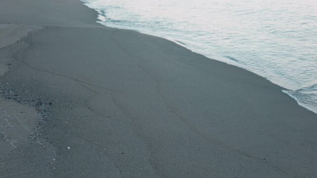 Gentle Waves Breaking on a Wide Blue-Gray Sandy Beach