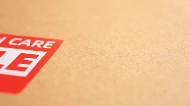 Close up of fragile shipping label on brown cardboard box surface motion.