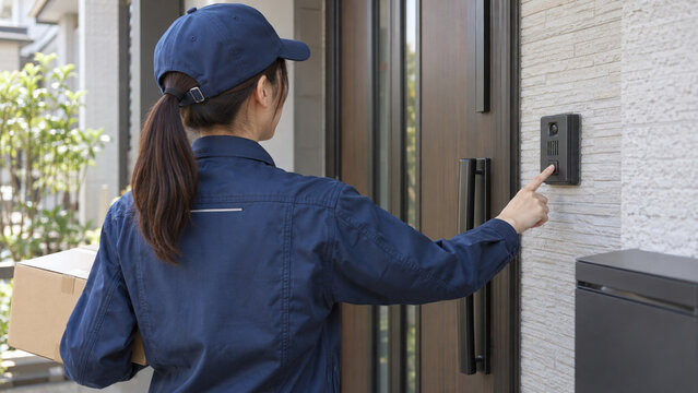 Female Courier Pressing a Door Intercom during a Home Delivery