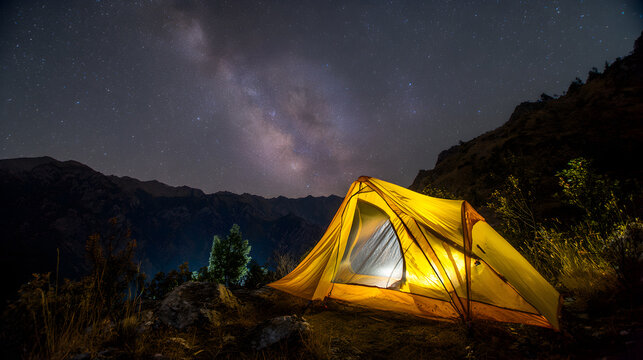 Bright yellow camping tent illuminated at night in the mountains