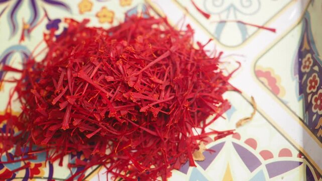 Close up motion footage showing vibrant red saffron threads arranged on decorative tray.