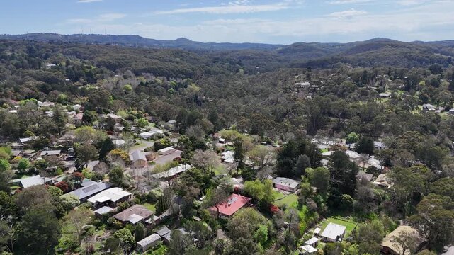 Aerial drone view of lush, tree-covered township of Bridgewater in the Adelaide Hills, South Australia. Regional residential homes within dense native eucalypt canopy and rolling forested ridges