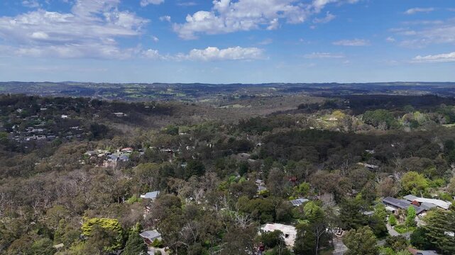 Aerial drone view of Bridgewater in the Adelaide Hills, South Australia, Australia, with scattered houses hidden among dense eucalyptus trees and bushland, looking out across a valley and rolling hill