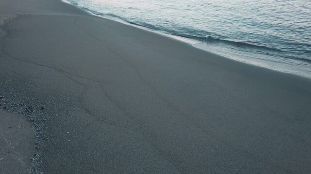 Gentle Waves Breaking on a Wide Blue-Gray Sandy Beach