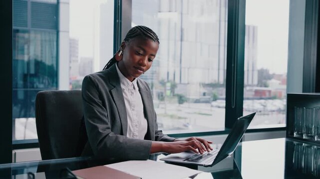 Laptop, typing and black woman in office with paper for financial report, audit review or accounting. Reading document, computer and person in corporate enterprise, income statement or balance sheet