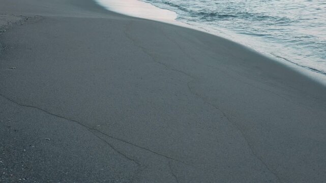Gentle Waves Breaking on a Wide Blue-Gray Sandy Beach