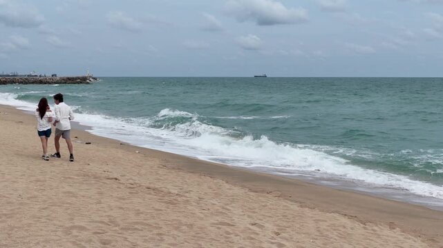 Young Couple Walking Along Sandy Beach Near Ocean Waves