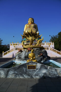 A large brilliantly gold-colored statue of Phra Maha Kaccayana Thera, holding a holy water vessel representing the 76 provinces standing 20 meters at Wat Lang San Prasit.