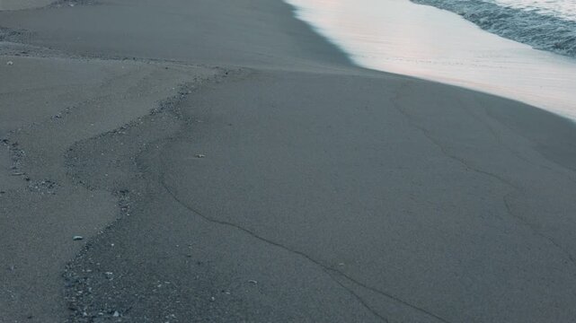 Gentle Waves Breaking on a Wide Blue-Gray Sandy Beach