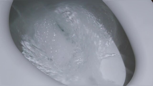 Swirling water flushing rapidly down a clean white ceramic toilet bowl.