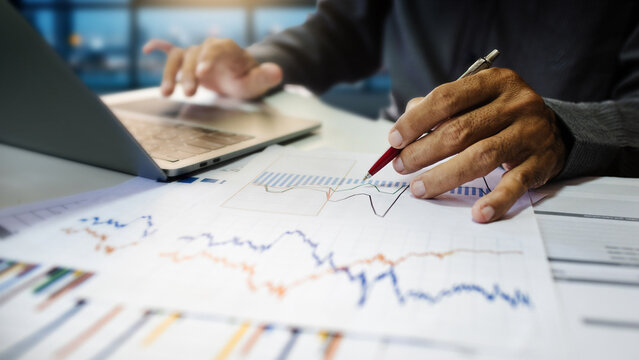 close-up shot, businessman using laptop work on desk in office  analyzing investment chart to make investment plan