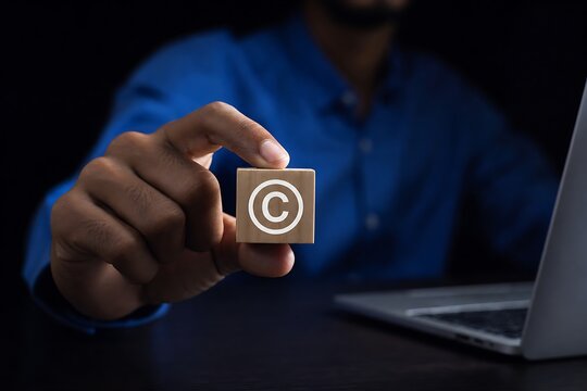Businessman holding wooden block with copyright symbol near laptop in dark office