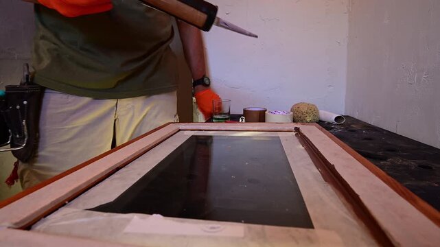 Carpenter applying brown silicone sealant on a wooden window frame