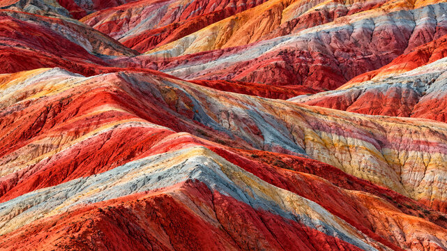 A composite landscape of Danxia landform and colorful hills,Vividly colored layered rock formations in a dramatic desert canyon landscape, ideal for travel and nature design projects