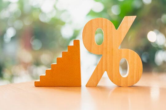 Tiered interest rate and financial ladder concept, wooden percentage sign standing beside rising steps staircase on table, symbolizing incremental savings yield, investment growth, and loan.