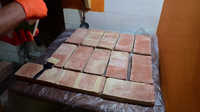Worker applying a protective coating to terracotta bricks