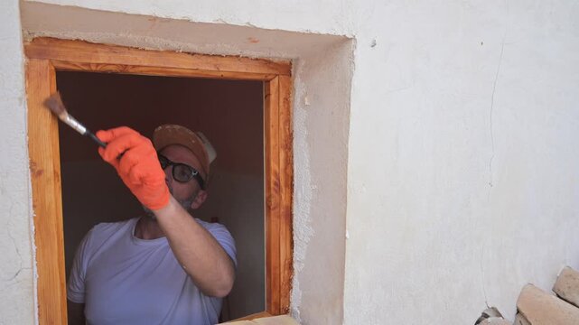 Middle-aged man carefully painting a wooden window frame