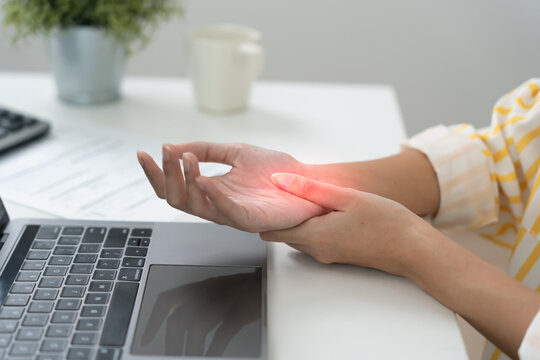 business young woman working in office with a carpal tunnel syndrome or wrist joint inflammation, hand muscle inflammation from office syndrome , hand muscle pain from working