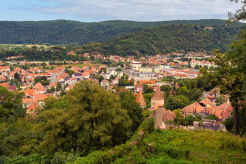 Obraz premium Elevated city view across Sighisoara with historic towers red rooftops and forested hills in Romania