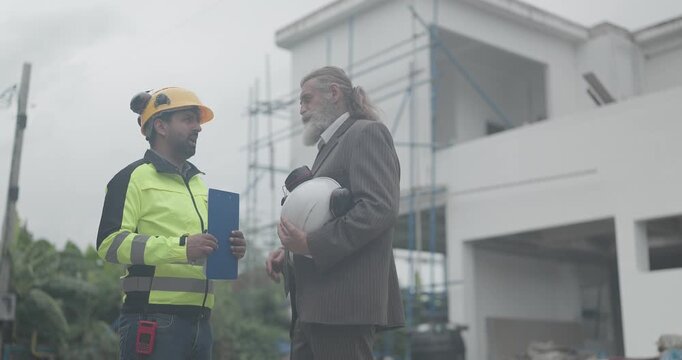 Engineer and businessman meeting and inspecting house exterior at outdoor construction site