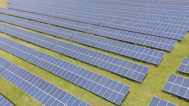 Rows of solar panels stretch across green grass