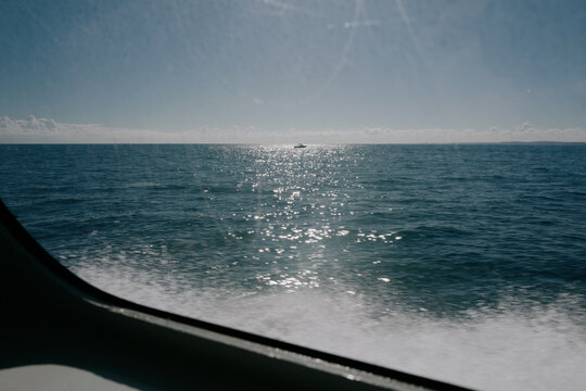 Sparkling sea view from a boat with distant motorboat on the hor