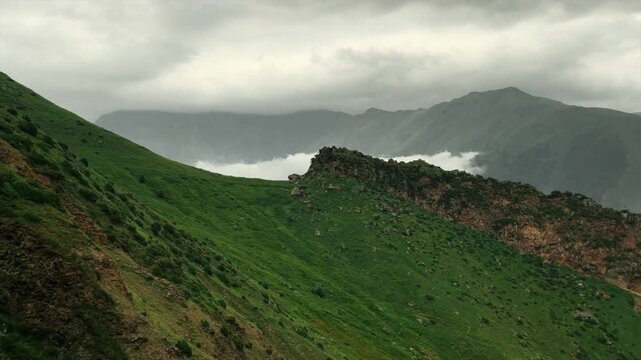Lush green mountainside under a cloudy sky
