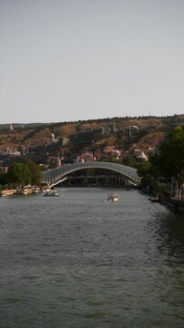 Boats on the Mtkvari river with the Bridge of Peace in Tbilisi