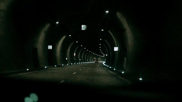 POV driving through a dark modern illuminated tunnel