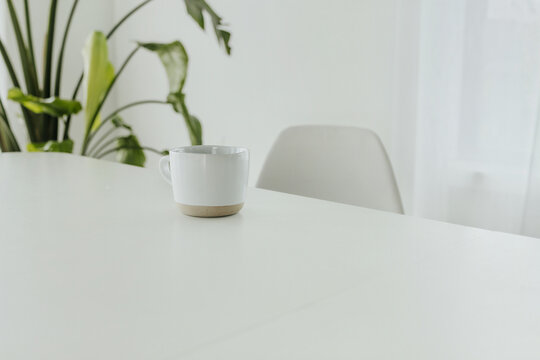 Minimalist scene of a coffee cup on a white table