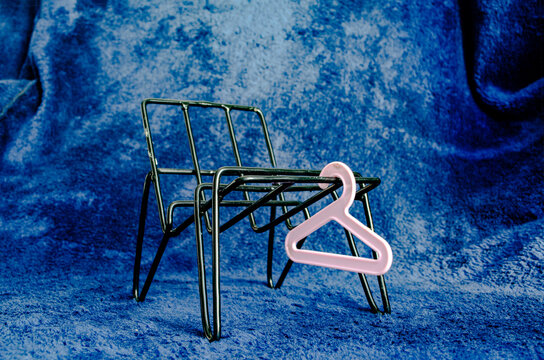 Small wire chair with a pink hanger on a blue background