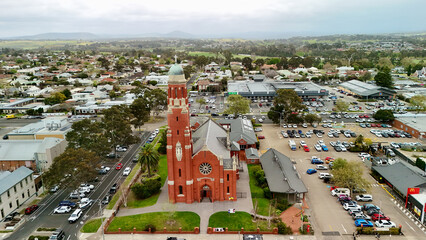 Fototapeta premium Bairnsdale, Victoria, Australia – 4K aerial drone view of regional city centre, St Mary’s Catholic Church, Main Street, roundabouts, residential areas and East Gippsland countryside