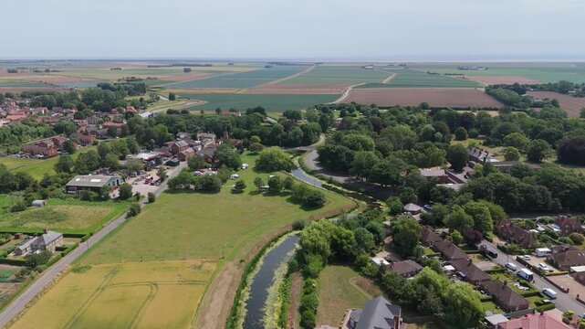 Drone glides above peaceful village nestled in green fields