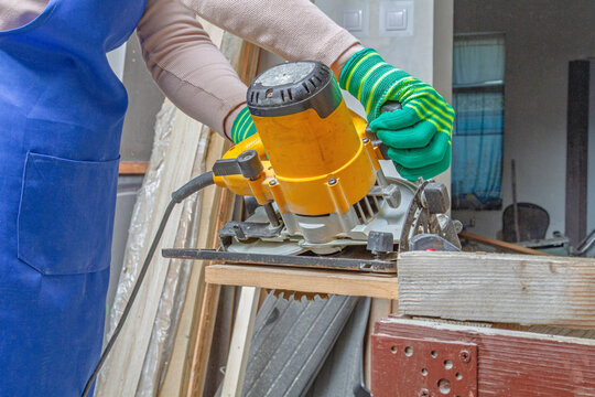 Worker operating a circular saw to cut lumber at an angle in a workshop. Close view of power tool and timber. Carpentry and woodworking. Construction, renovation and DIY home improvement