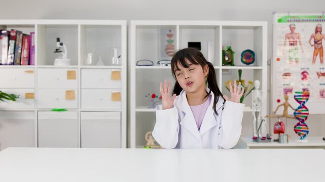 Cute Little Girl in Lab Coat Gesturing in Science Classroom