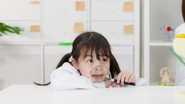 Little Asian Schoolgirl in Lab Coat Playing with Magnifying Glass